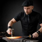 studio photograph of Christoph Gey dressed as a blacksmith in a black flat cap, short sleeve shirt, and vest, hammering a glowing red katana blade on an anvil, sparks flying from the forge in the background, dramatic lighting, sharp focus, dark background, industrial setting, masculine aesthetic